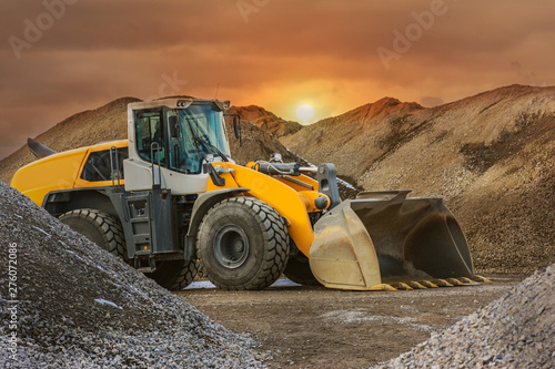 Fotografie Excavator in a construction site, surrounded by stone and rock