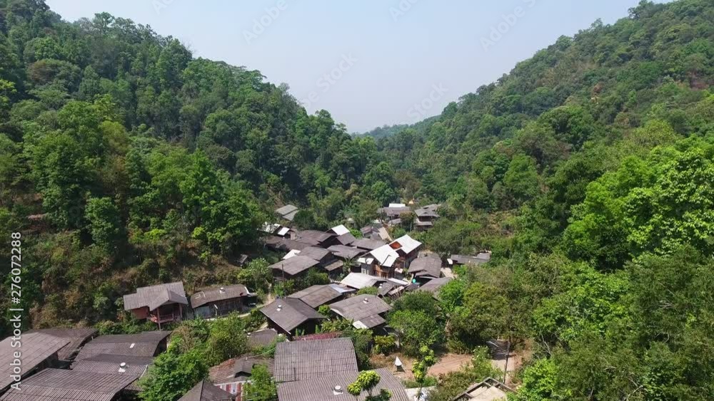 A high angle shot of a village settlement situated at the low point between two mountains covered with trees A high angle shot of a village settlement situated at the low point between two mountains covered with trees