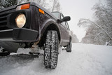 Wheels off-road car on a snowy road in the Russian outback. Winter adventures to overcome hard-to-reach forest areas.