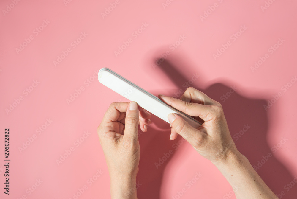 Woman filing nails in colored background Woman filing nails in colored background