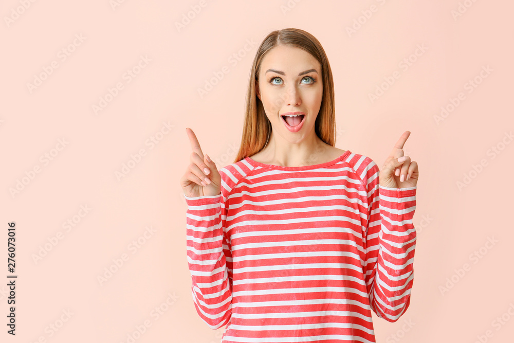 Beautiful young woman pointing at something on color background Beautiful young woman pointing at something on color background
