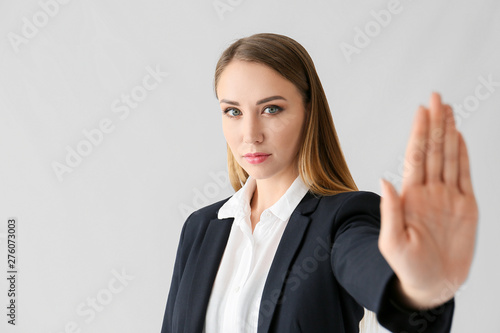 Young businesswoman showing STOP gesture on white background