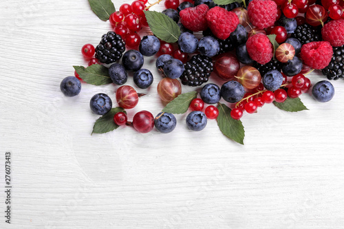 Delicious berries in a bowl, currants, blackberries, blueberries, raspberries on a white wooden table. place for text. top view. frame