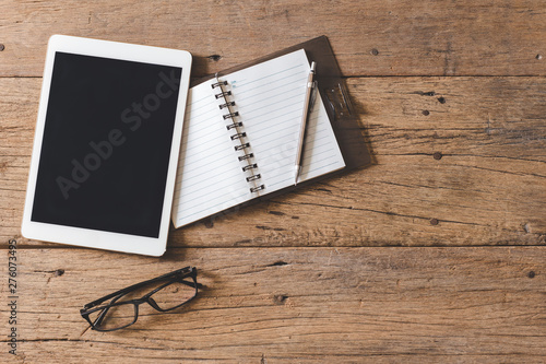 Top view of Pen  notebook  glasses  tablet on wooden table and copy space