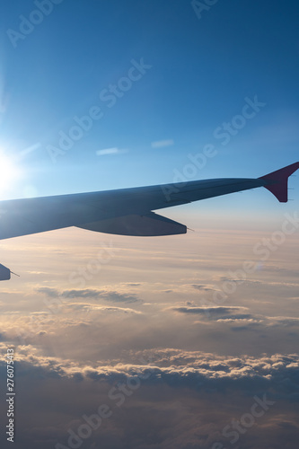 Up in the air, view of aircraft wing silhouette with dark blue sky horizon and cloud background in sunset time, viewed from airplane window