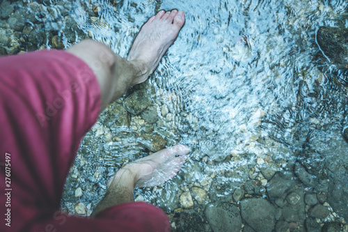 Hiking outdoors in the forest  Cut out of male barefoot feet in a shallow river  fresh water