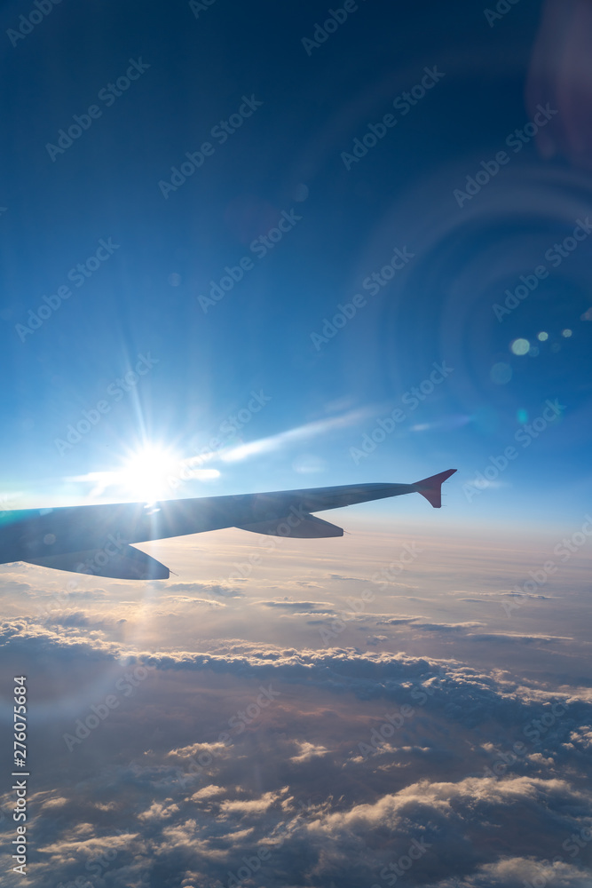 Up in the air, view of aircraft wing silhouette in dark blue sky horizon and cloud background in sunset time. viewed from airplane window, with a reflection camera lens