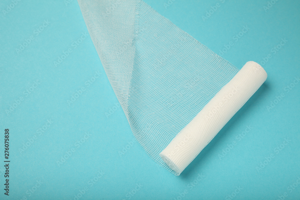 Fototapeta premium White gauze bandage on blue background. First aid, injury treatment.