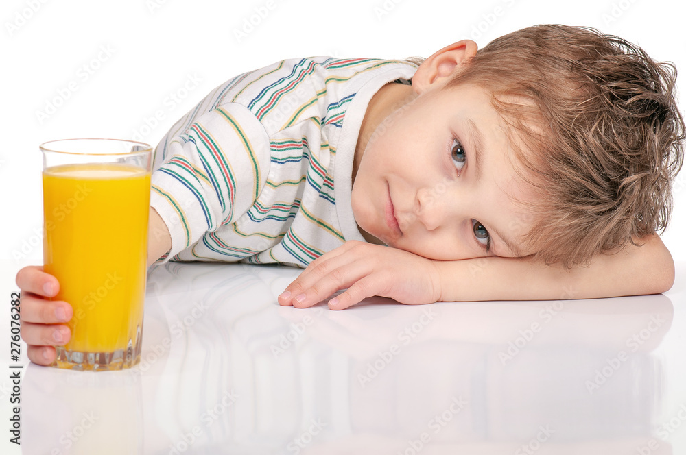 Portrait of little boy with glass of orange juice sitting at table on white background. Portrait of little boy with glass of orange juice sitting at table on white background.