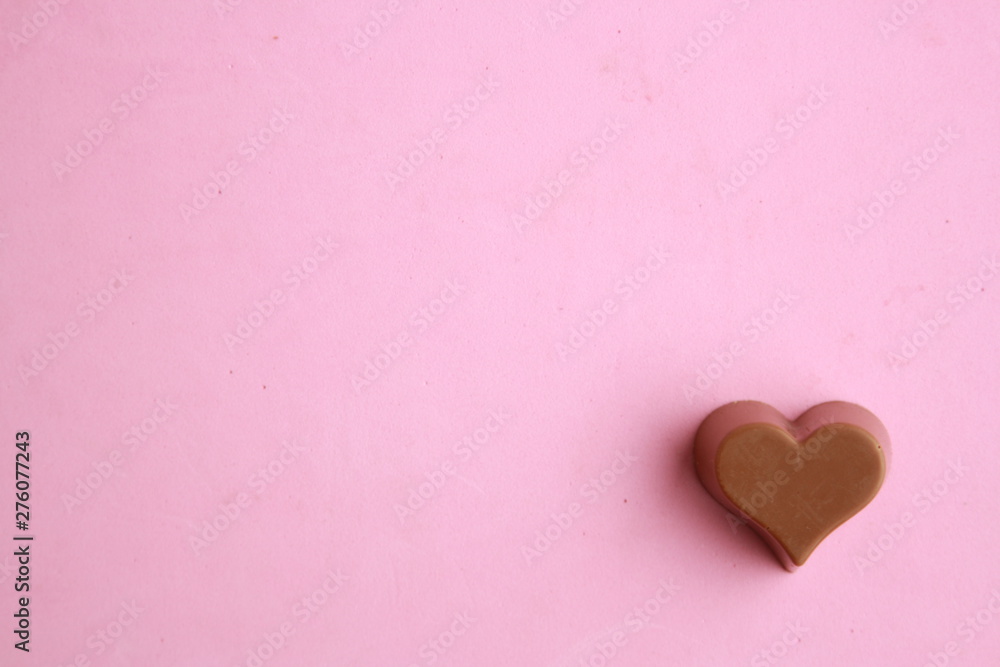 Chocolate bonbon with heart shape in color background