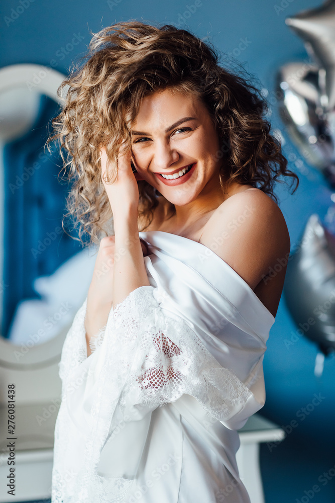 Naklejka premium Birthday, blonde woman posing to camera in luxury hotel with balloons behind.. Blue bedroom.