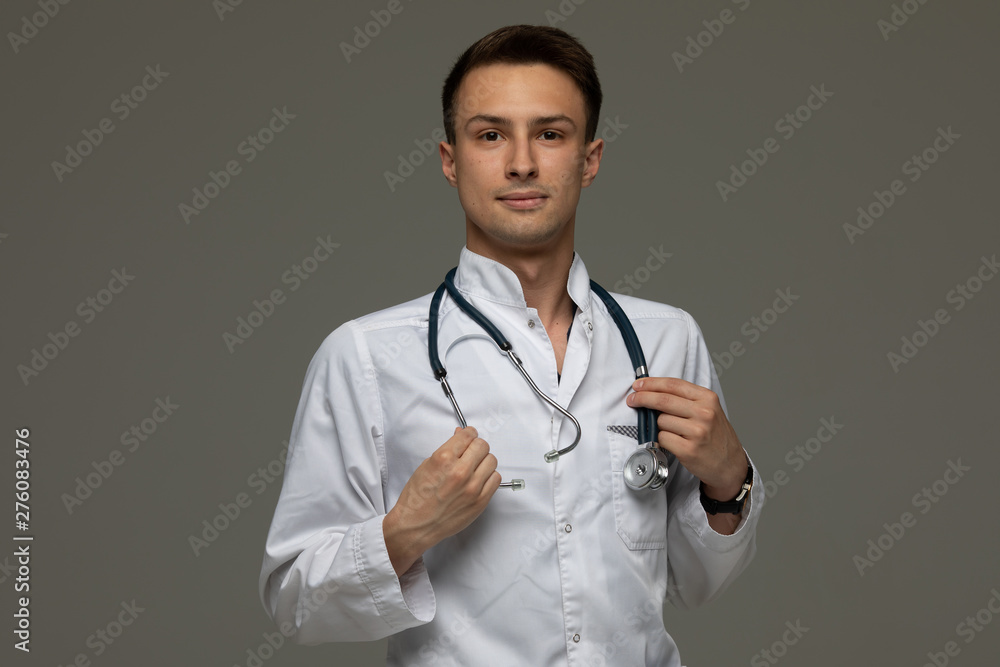 Portrait of young doctor smiling on grey background Portrait of young doctor smiling on grey background