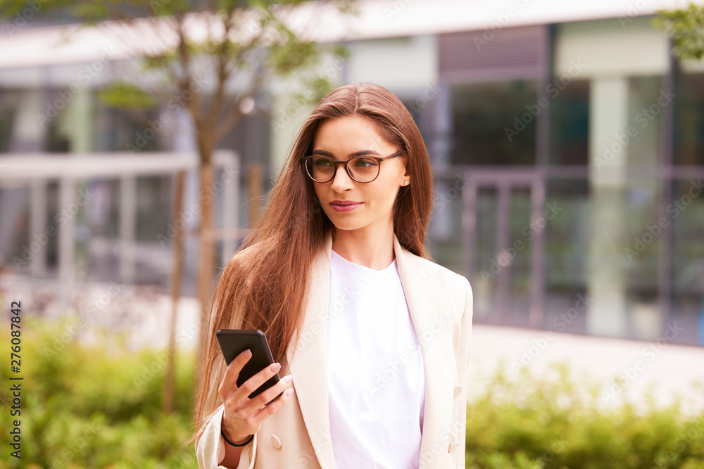 Young businesswoman text messaging while walking on the street in the city Young businesswoman text messaging while walking on the street in the city