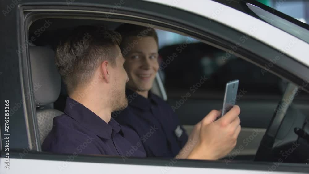 Male police officers chatting smartphones in car during work brake, rest Male police officers chatting smartphones in car during work brake, rest