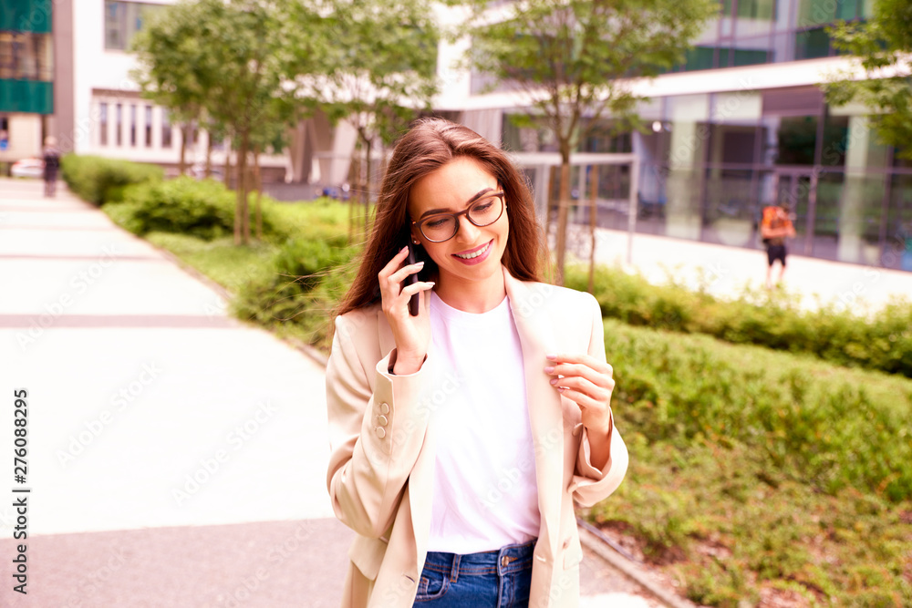 Young businesswoman making a call while walking on the street