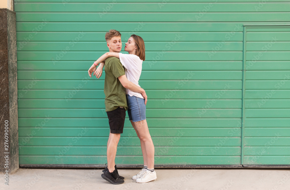 Young handsome people hug on a green background, a funny guy looking to the  side. Funny