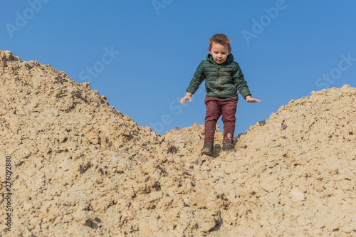A little boy is climbing a sand mountain. © Konstiantyn Zapylaie