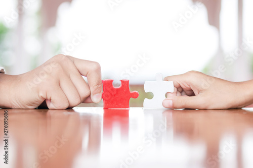 hands holding piece of red jigsaw puzzle. teamwork concept