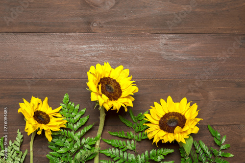 Sunflowers and fern leaves on wooden background