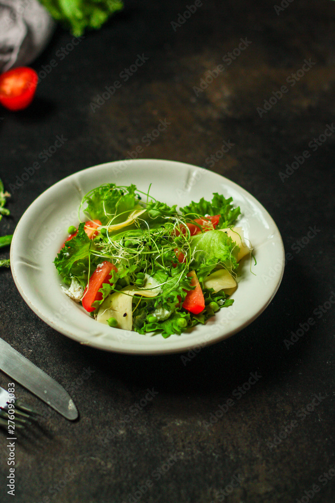 salad with tomato, lettuce, arugula and other green leaves. food background. top salad with tomato, lettuce, arugula and other green leaves. food background. top