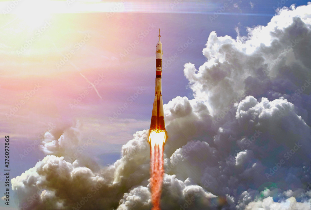 Dramatic launch. Rocket launching. Blue sky. CLouds and sun flare. Elements of this image furnished by NASA.