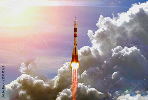 Dramatic launch. Rocket launching. Blue sky. CLouds and sun flare. Elements of this image furnished by NASA. photo