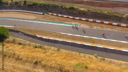 Aerial, tracking, drone shot, following a group of cyclists, bypassing other bikes, at a 24h cycling competition, on Autodromo do Estoril Circuit, on a sunny day, near Lisbon, Portugal photo