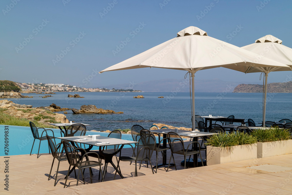Crete, Greece. June 2019.  Poolside table and chairs overlook the Chania Bay northern Crete.
