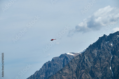 Red helicopter in the sky over the Caucasus Mountains, a beautiful mountain landscape.