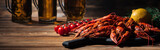 panoramic shot of red lobsters, tomatoes, dill, lemon and glasses with beer on wooden surface