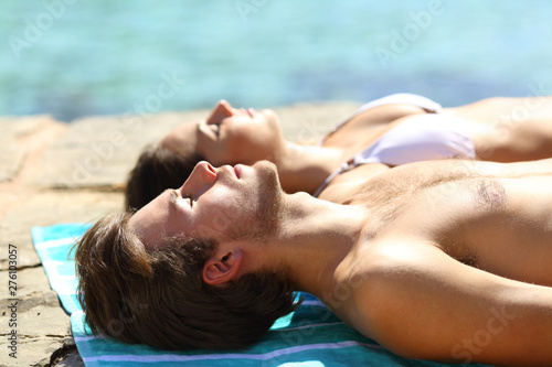 Fototapeta Couple sunbathing on summer vacation on the beach