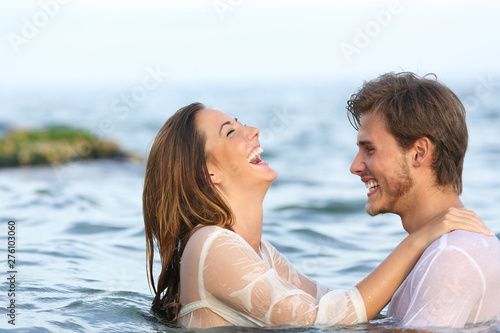 Happy couple joking in the water on the beach