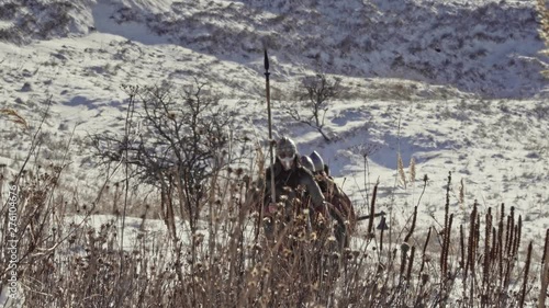 Group of medieval vikings with arms and shields going on the winter meadow. photo