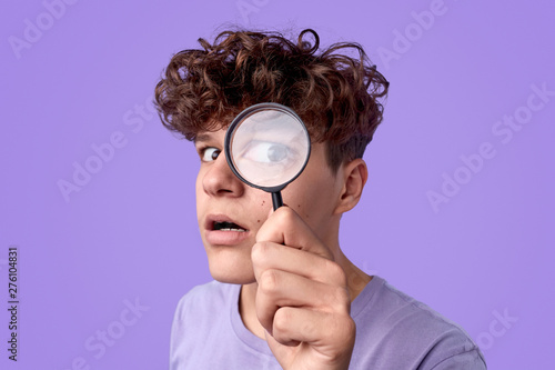 Funny teenager looking through magnifying glass photo