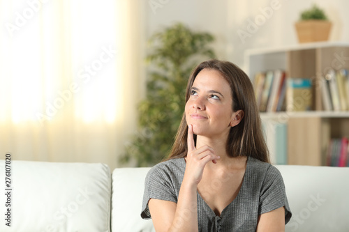 Smiley woman thinking looking at side at home
