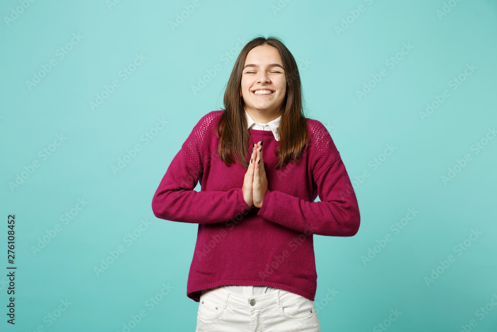 Young brunette woman girl in casual clothes posing isolated on blue green turquoise background studio portrait. People sincere emotions lifestyle concept. Mock up copy space. hands folded in prayer. Young brunette woman girl in casual clothes posing isolated on blue green turquoise background studio portrait. People sincere emotions lifestyle concept. Mock up copy space. hands folded in prayer.
