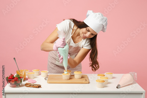 Canvas Print Cute housewife chef cook confectioner or baker in white t-shirt, toque chefs hat cooking at table isolated on pink pastel background in studio