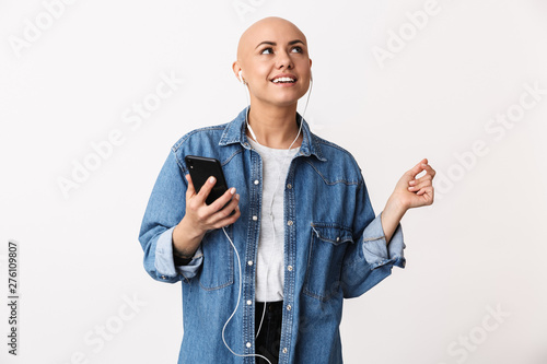 Fotografija Bald woman posing isolated over white wall background listening music with earphones using mobile phone