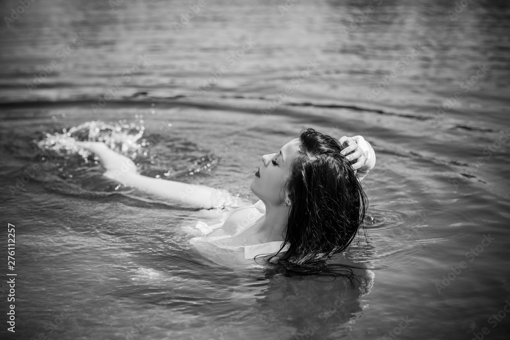 Fototapeta premium Woman in water. Model posing in white wet shirt at summer days 