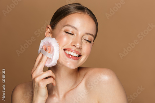 Beautiful young amazing woman posing isolated over brown chocolate background wall holding powder puff. photo