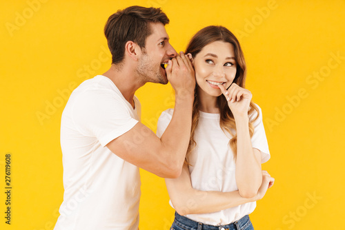 Portrait of handsome man whispering secret or interesting gossip to pretty woman in her ear
