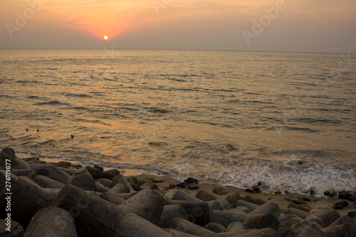 old sea concrete embankment with tetrapods against the background of ocean waves under the bright sunset sky