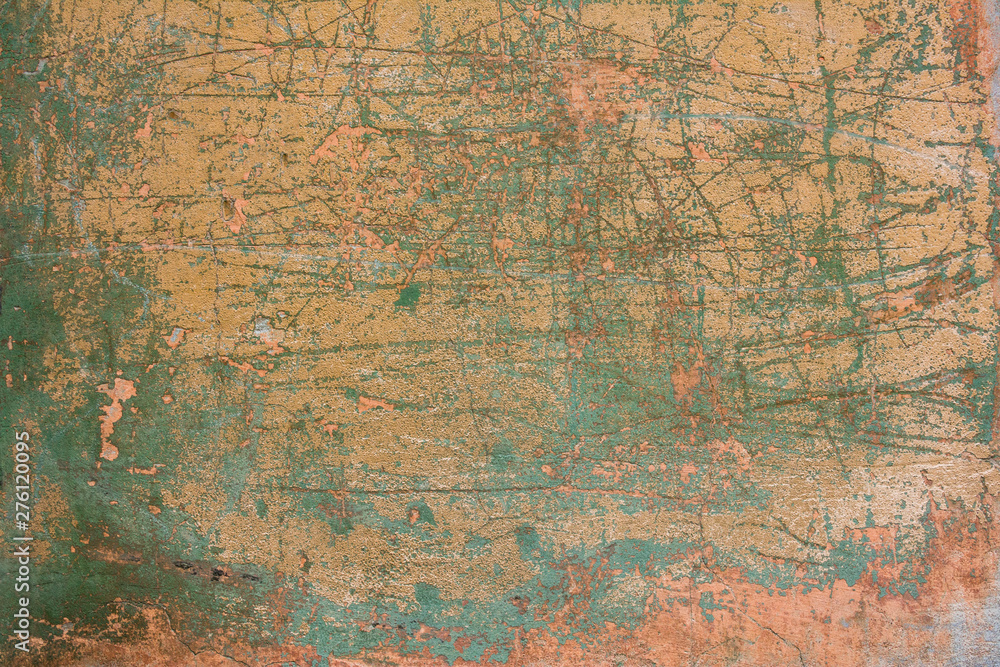 old shabby pink yellow concrete wall with cracks, deep scratches and stains of green paint and dirt. rough surface texture
