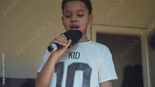 Cute african american boy singing karaoke at home. Handsome schoolboy trying to prepare himself for a song contest.
