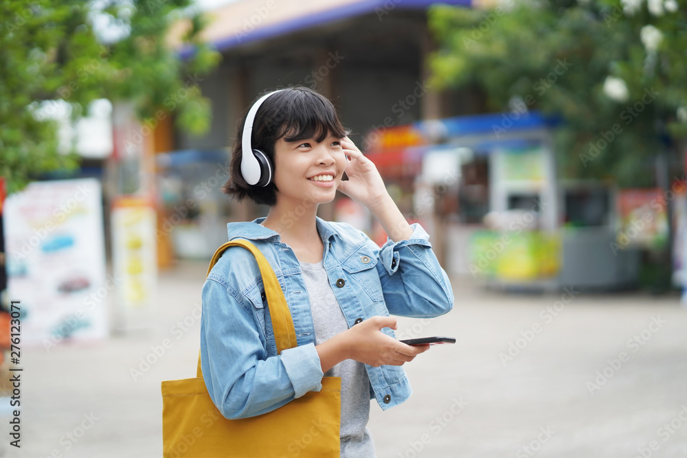 happy woman shopping with listening to music on smartphone and holding tote bag