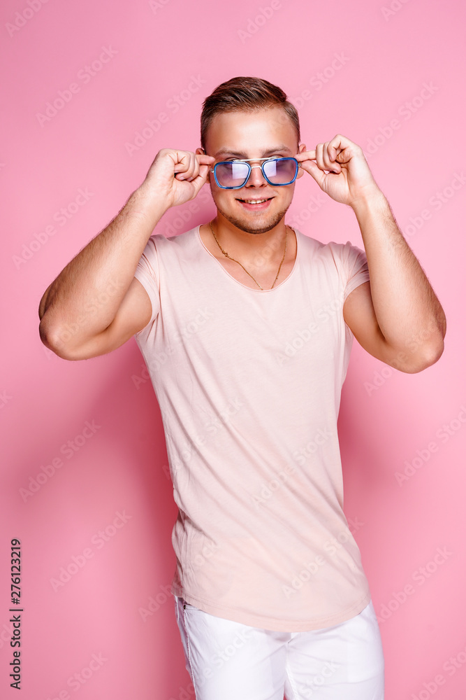 Positive young male in trendy outfit posing against pink background Positive young male in trendy outfit posing against pink background