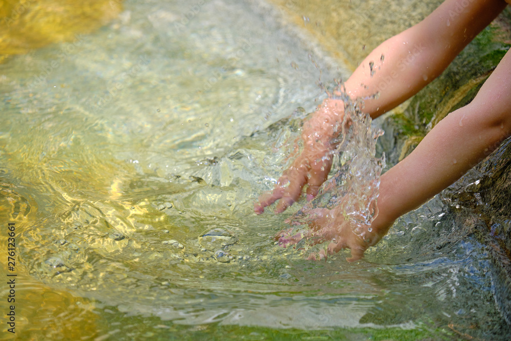 Young kids hands splashing around water in fountain to cool off, as the heat waves continue.  Close up on the water splash and the hands