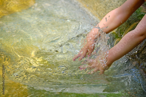 Young kids hands splashing around water in fountain to cool off, as the heat waves continue. Close up on the water splash and the hands
