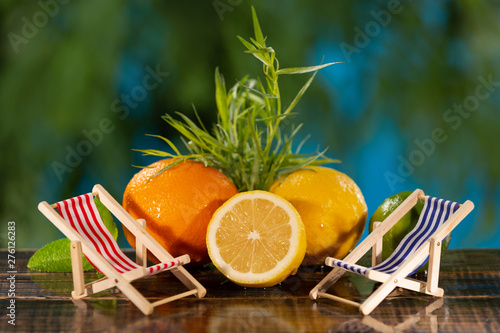 orange and lemon on the background of greenery, next to two small lounge chairs, the concept of vacation photo