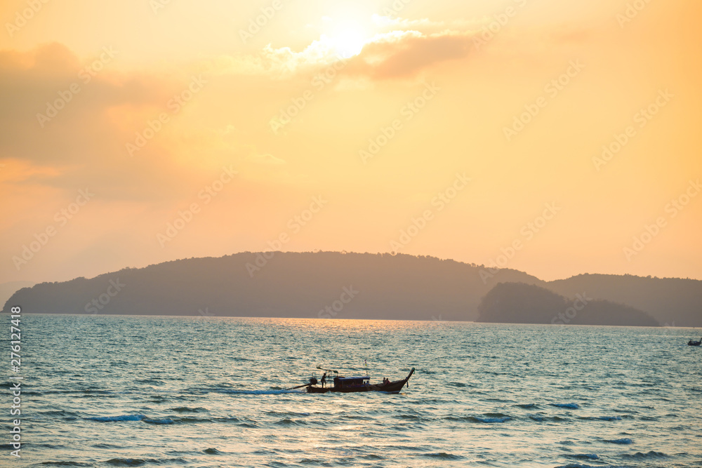 Beautiful sea landscape with small boat, blue coast and colorful sunset with bright sun